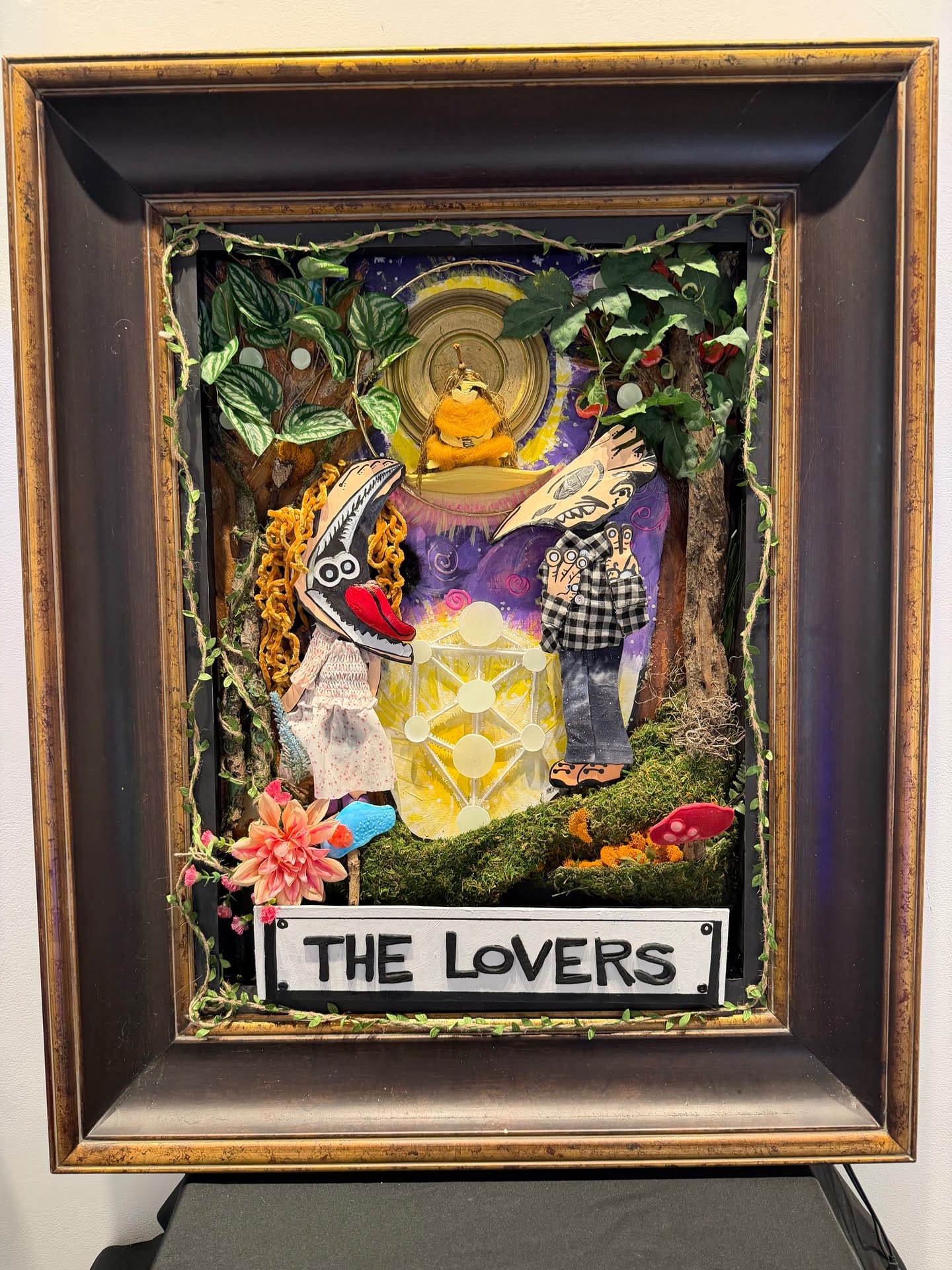 The Lovers, a framed mixed-media artwork with two figures, plants, and illuminated details
