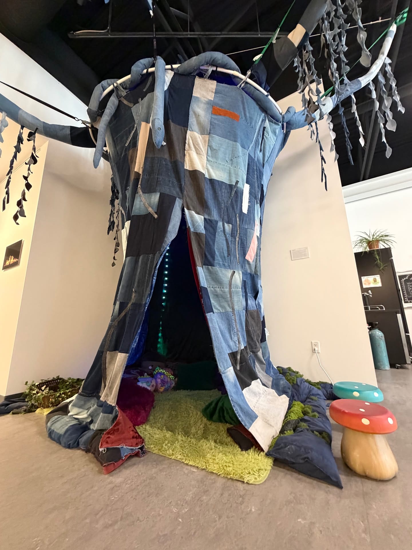 Walk-in patchwork textile installation with hanging fabric branches in the 2026 gallery