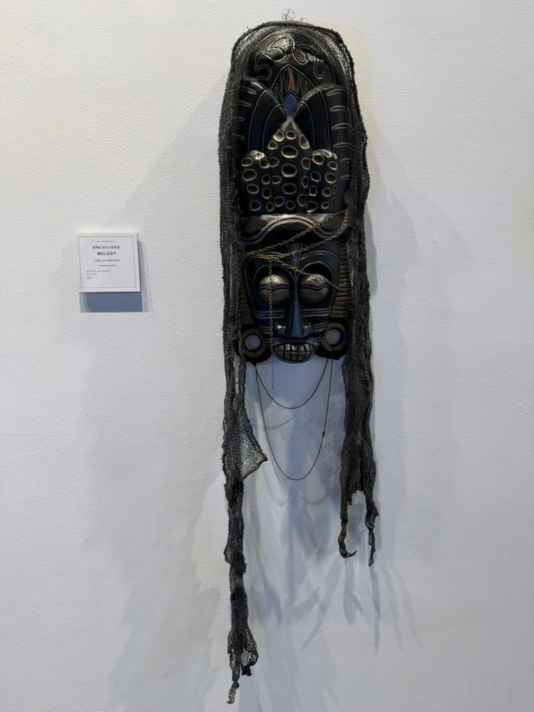 Unchained Melody, a tall black mixed-media mask with chains and hanging fabric in the 2026 gallery